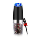 Black and silver pepper grinder with colorful peppercorns, a red ribbon, and a black spoon on a white background.